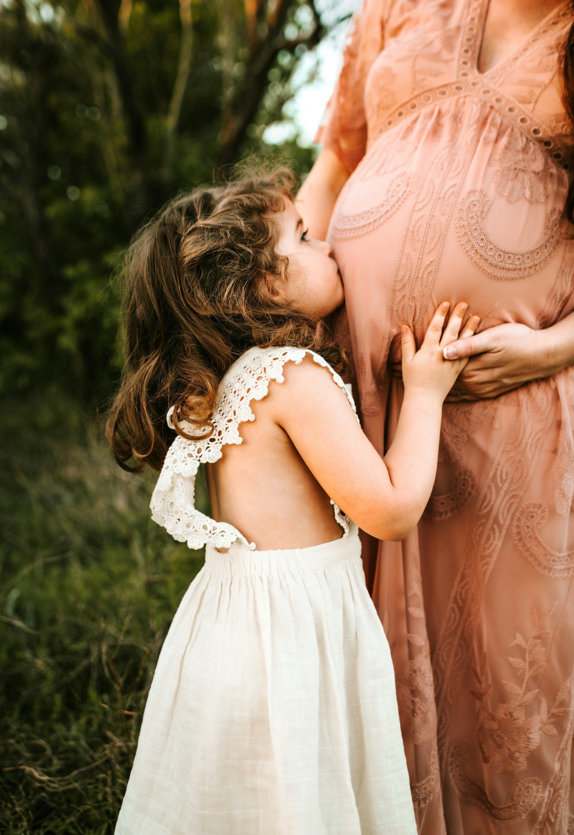child kissing pregnant woman's stomach