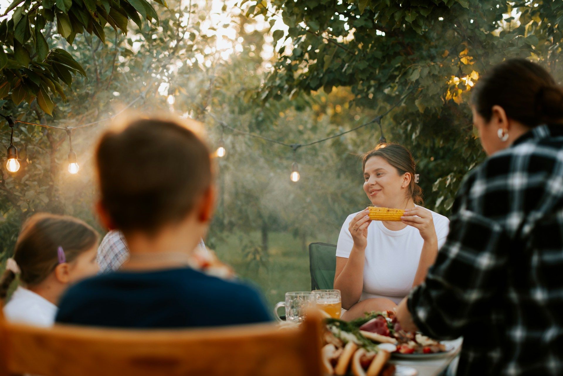 A family is sitting at a table eating corn on the cob.