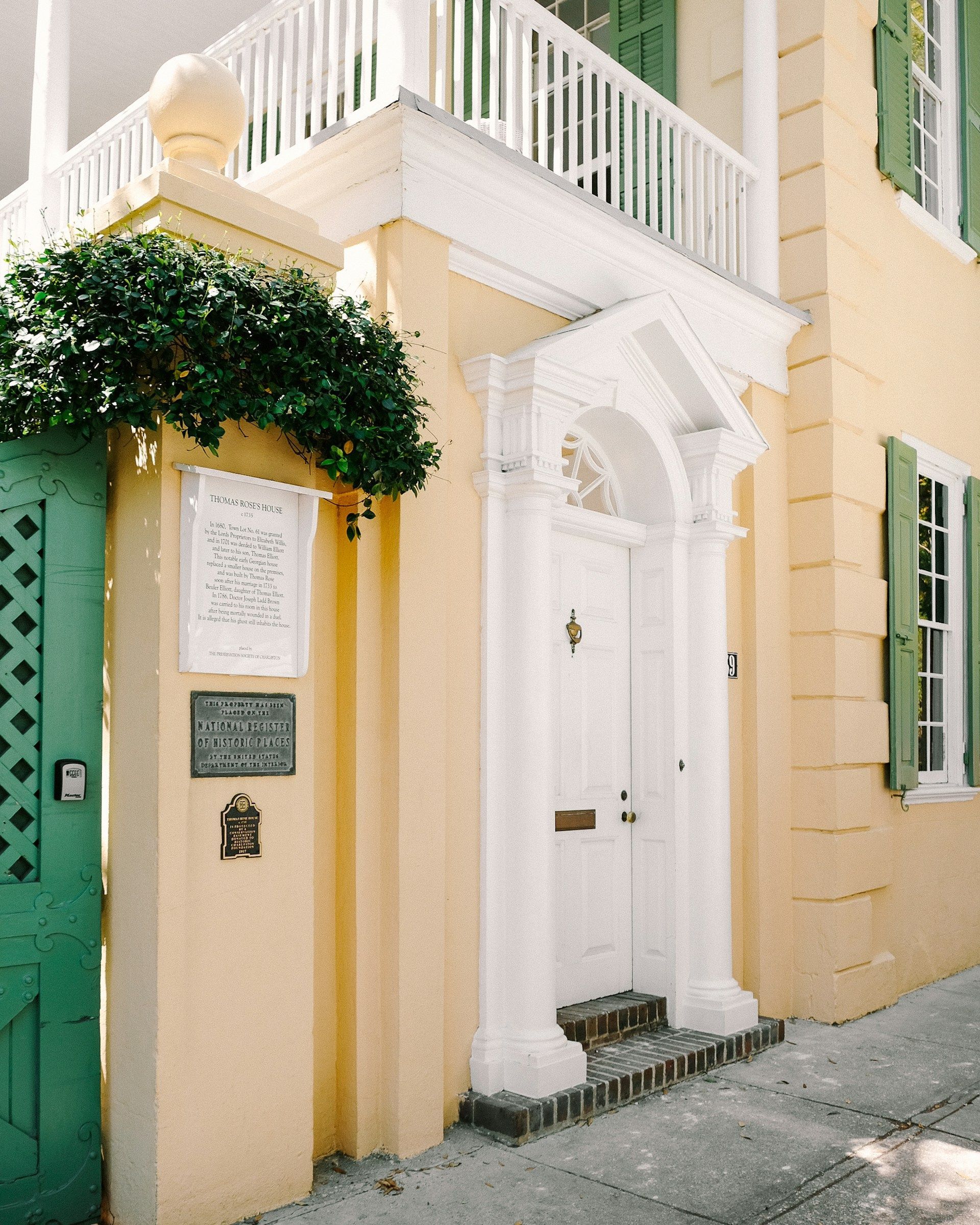 A yellow house with a white door and a green gate