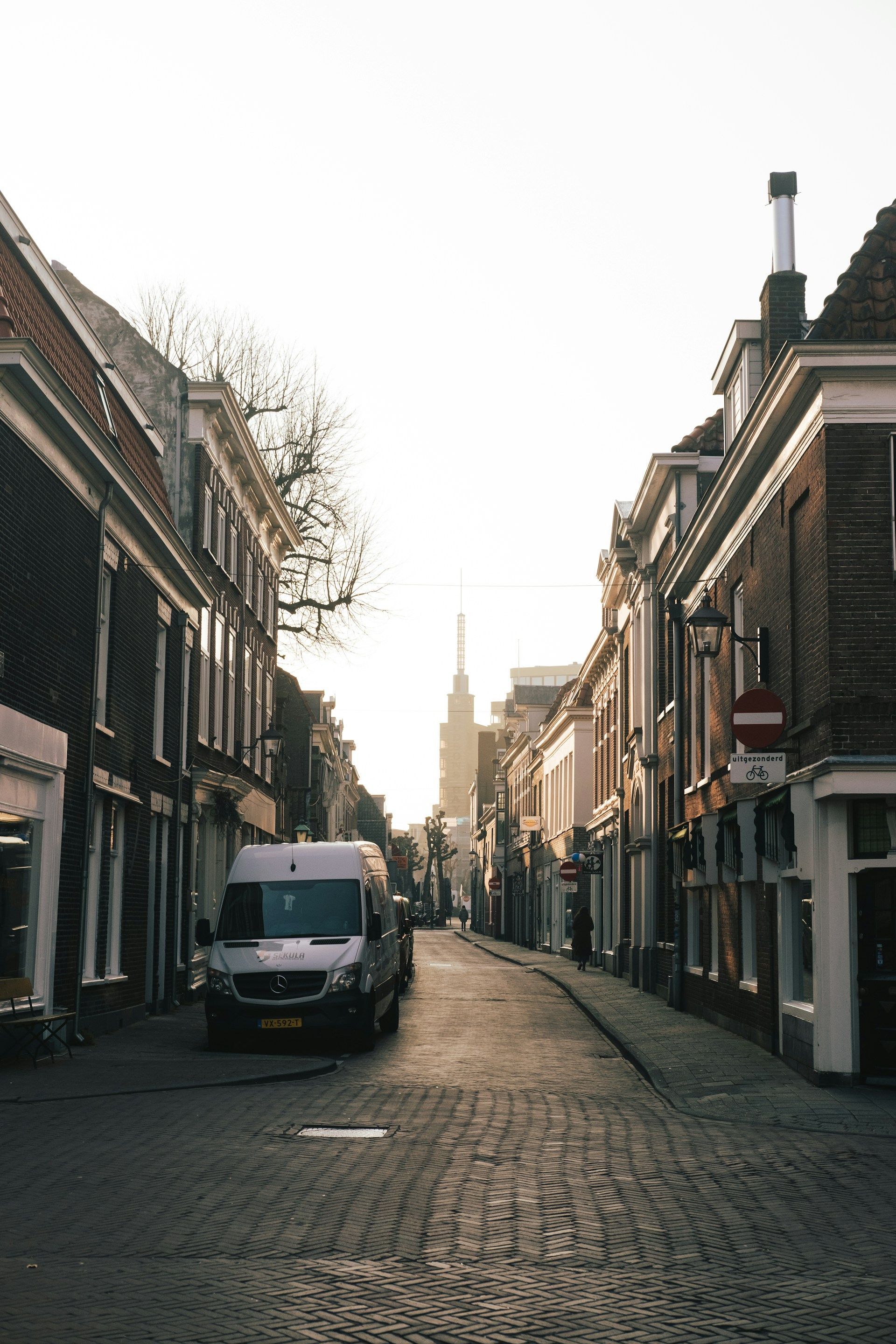 A white van is parked on the side of a cobblestone street