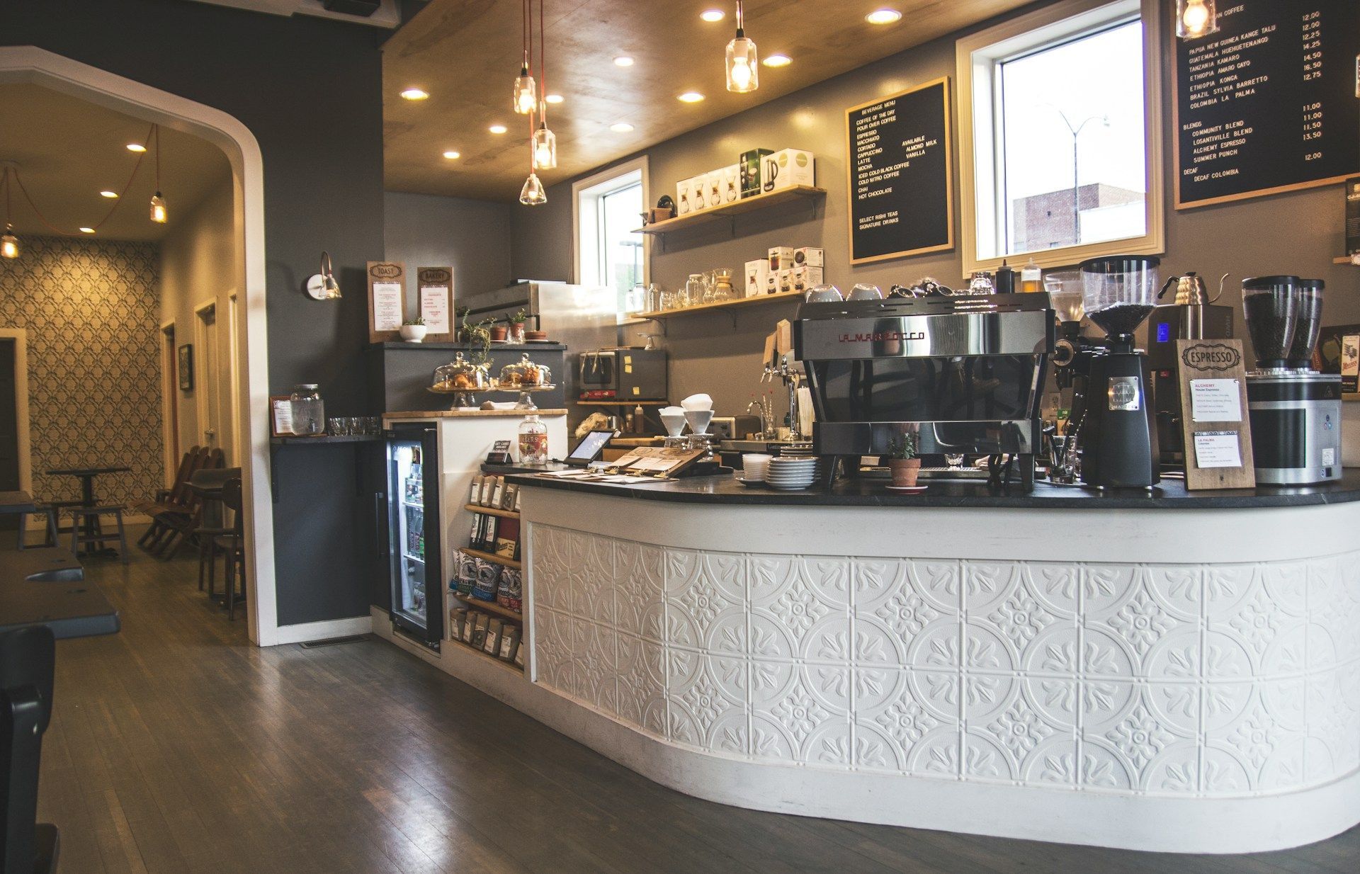 A coffee shop with a long counter and a chalkboard on the wall.