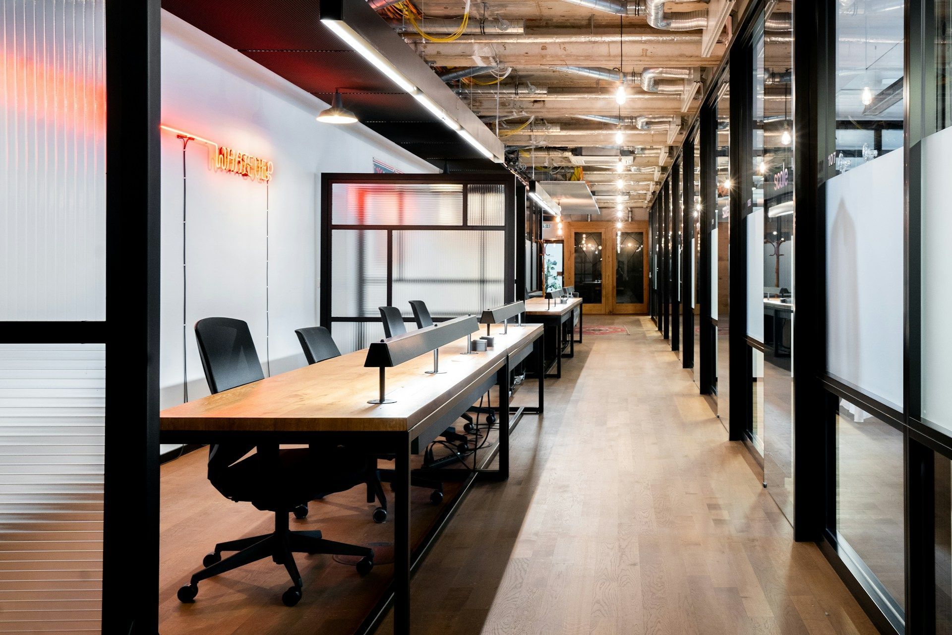 A long hallway with tables and chairs in an office.