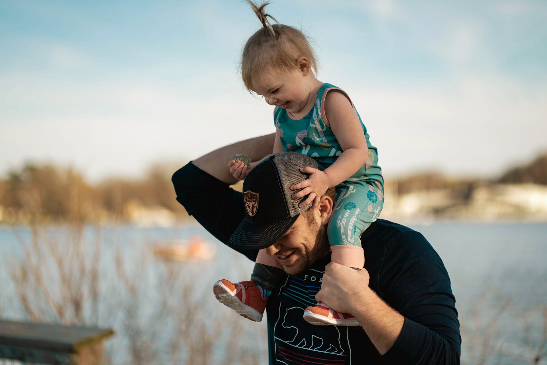 A man is carrying a little girl on his shoulders.