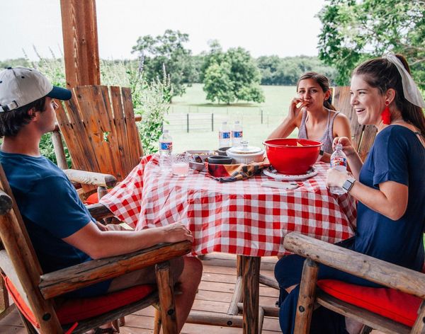 A group of people are sitting at a table with a red and white checkered tablecloth.