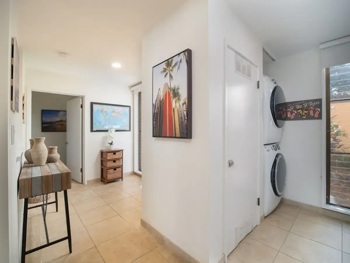 A hallway with a washer and dryer and a painting on the wall.