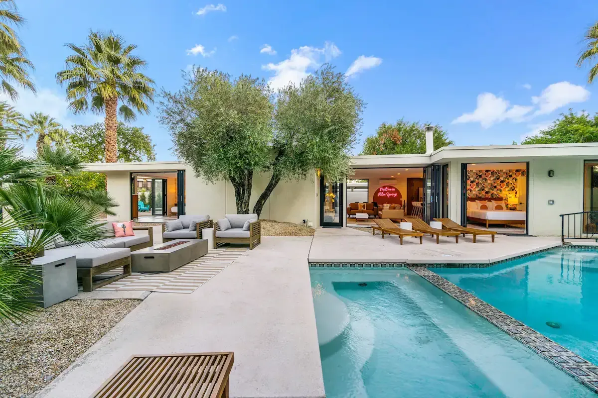 A house with a large swimming pool in front of it.