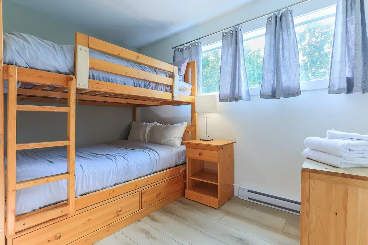 A bedroom with two bunk beds , a nightstand , and a window.