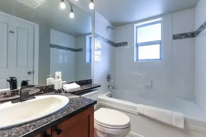 A bathroom with a sink , toilet , tub and mirror.