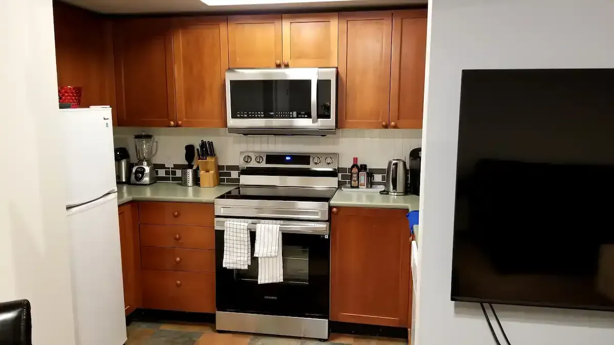 A kitchen with a stove , microwave , refrigerator and television.
