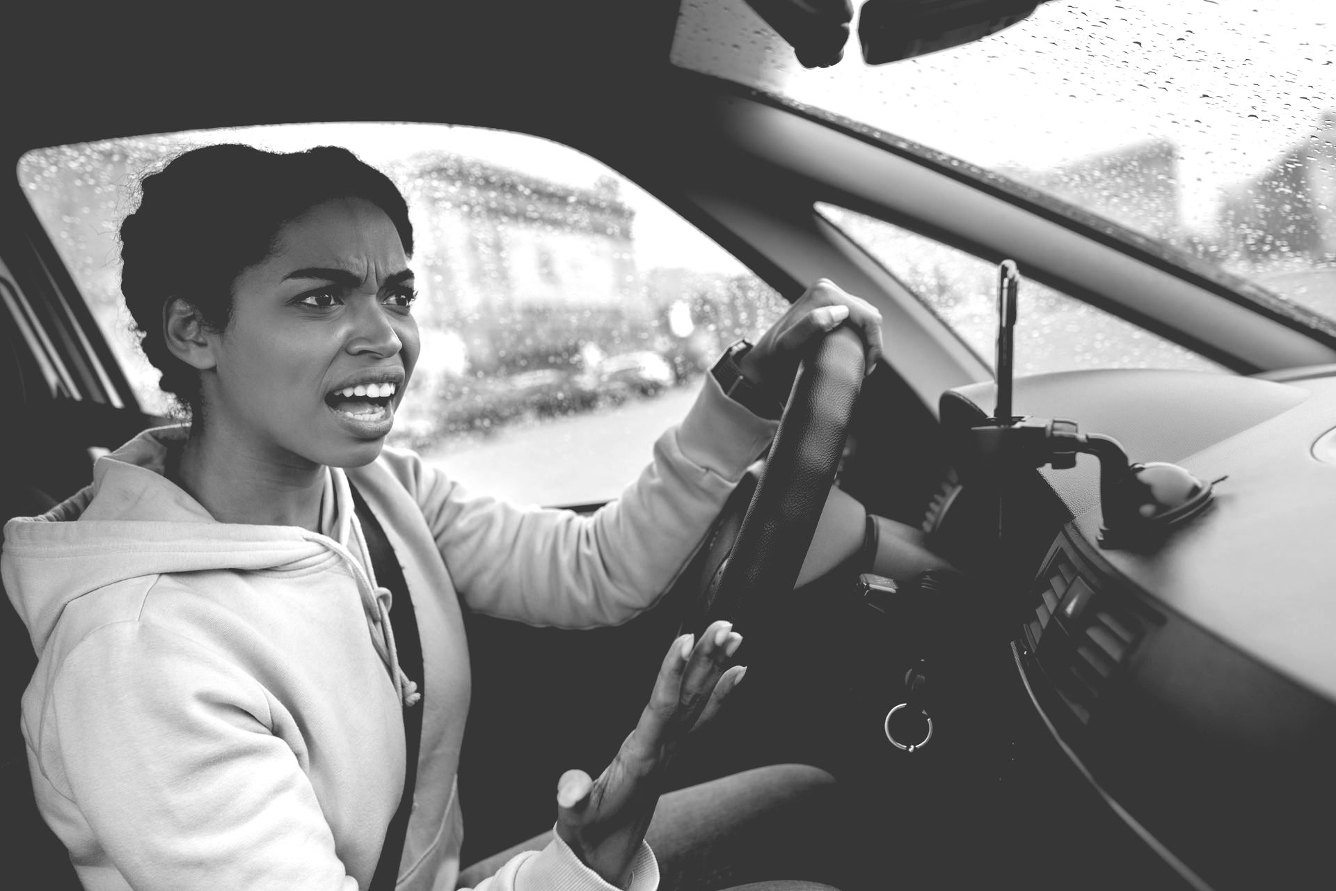 Driver speaking animatedly while driving a car in the rain