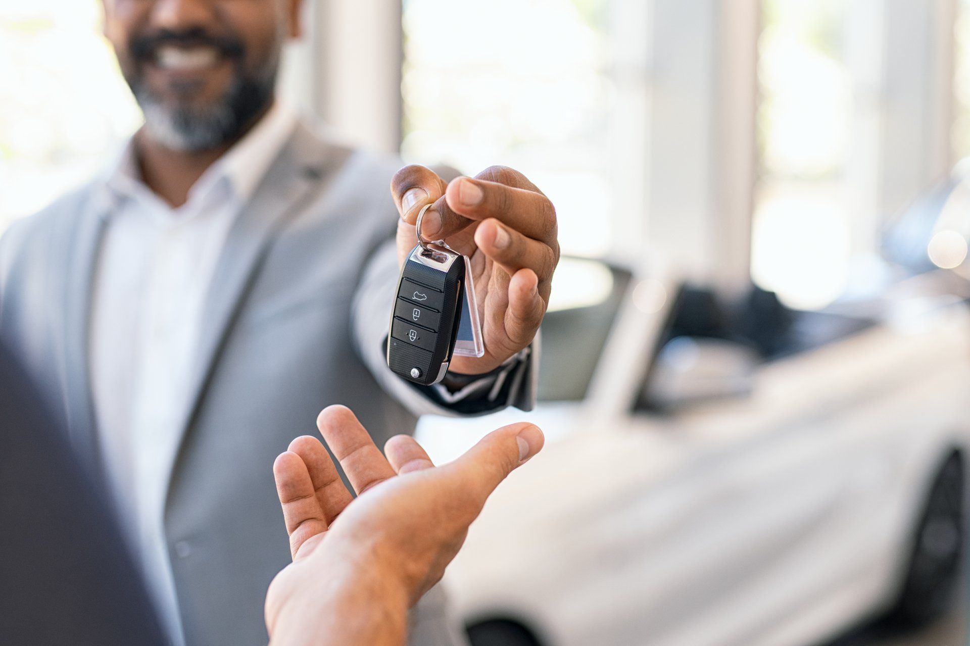 Closeup hand of cardealer giving new car key to customer.