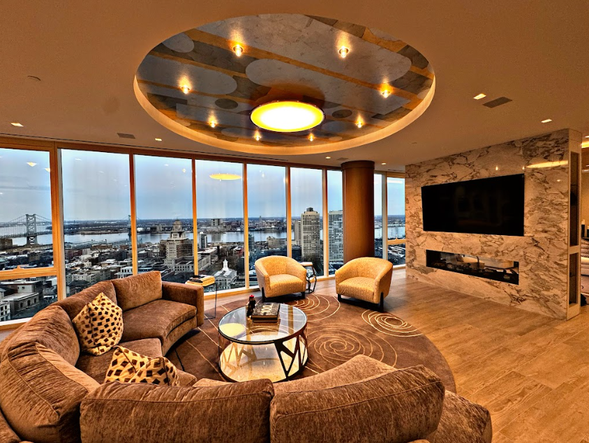 Modern high-rise living room with brown sectional, city skyline view, and stone accent wall