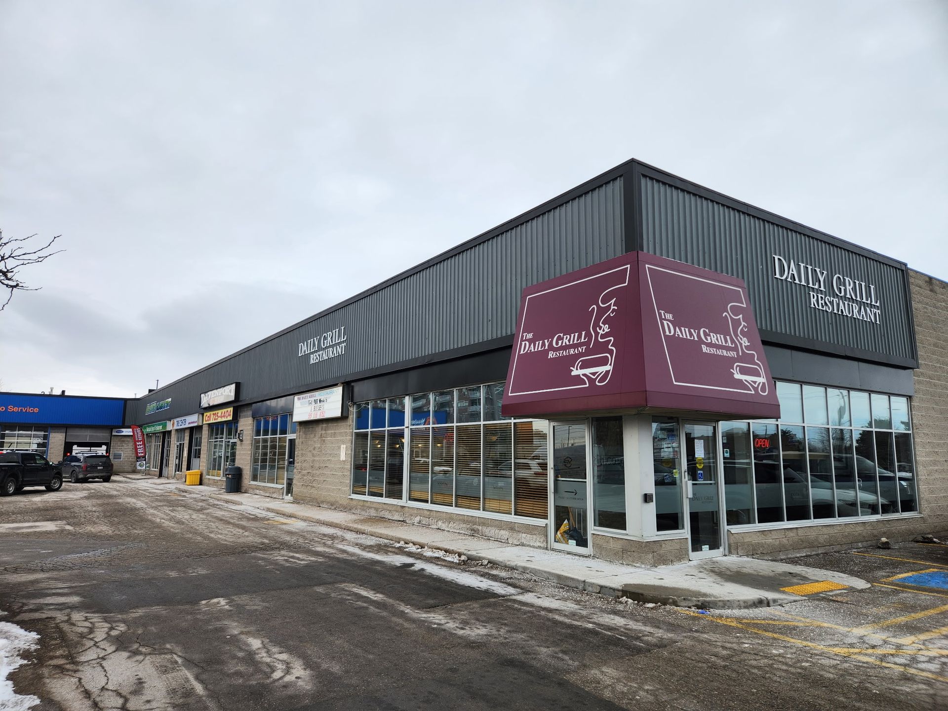 A commercial building with shops and a dark awning, snowy ground.