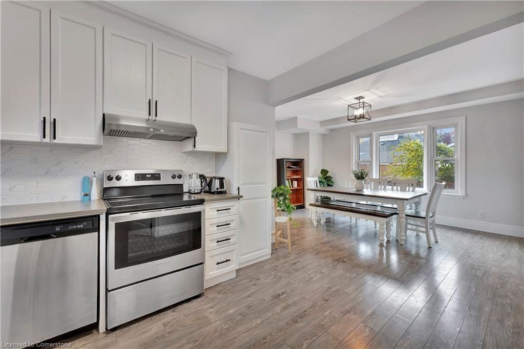 Kitchen with stainless steel appliances, white cabinets, and a dining area with a long table.