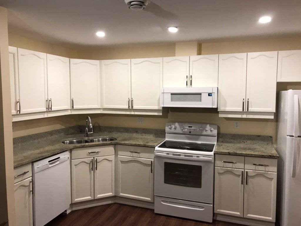 White kitchen cabinets, appliances, and countertops in a small kitchen.