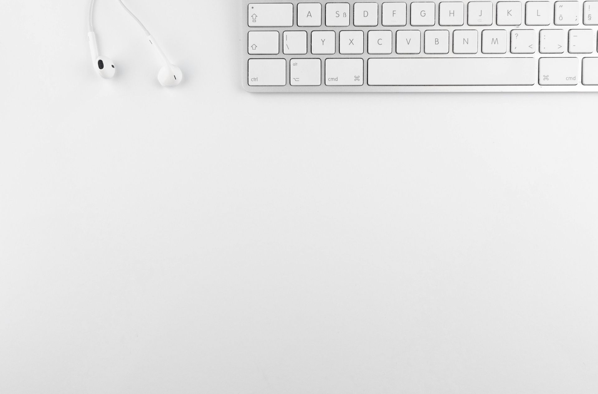 White keyboard and earbuds on a white background.