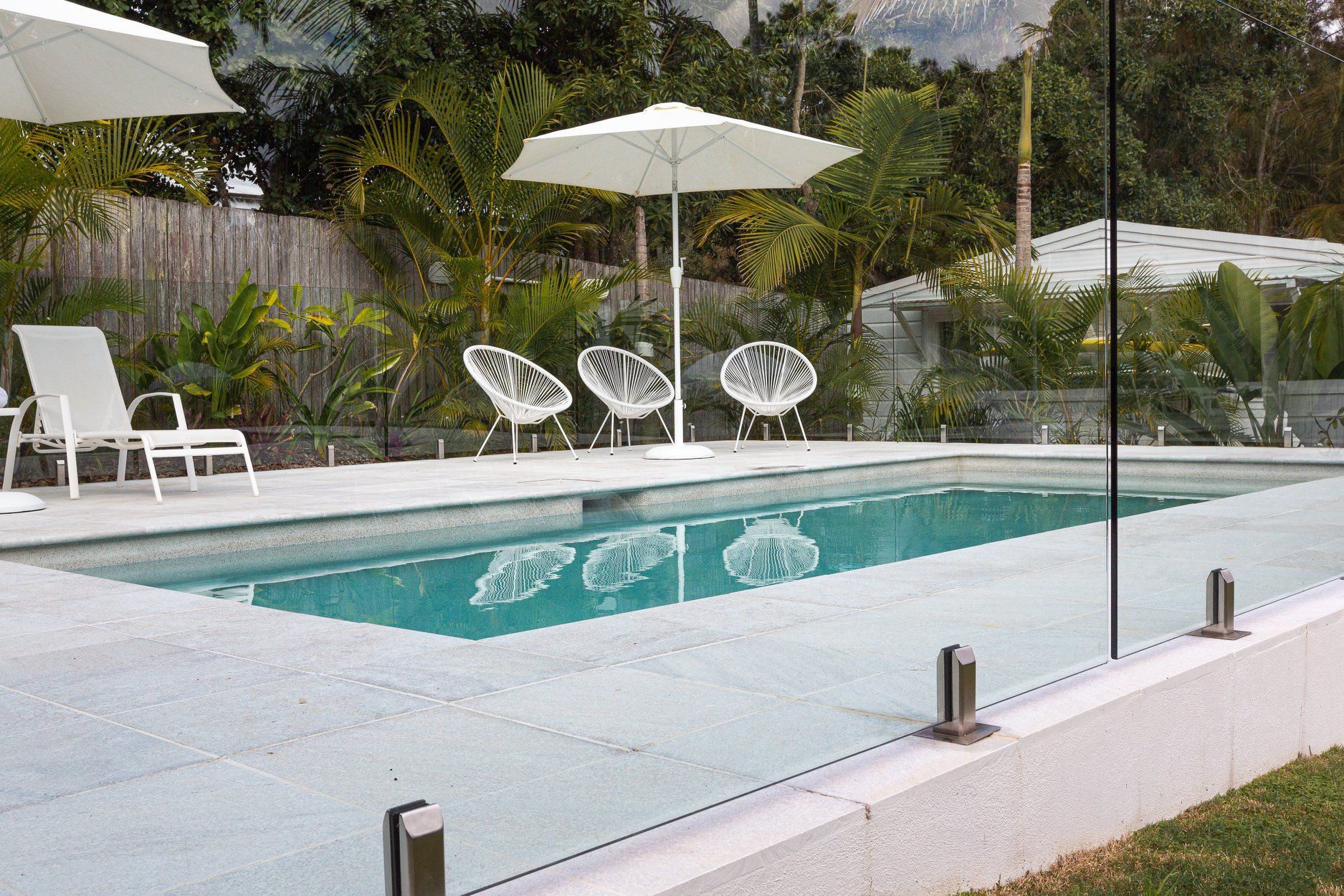 A Swimming pool with Chairs and Umbrellas around it — Profile Pools & Landscaping In Byron Bay, NSW