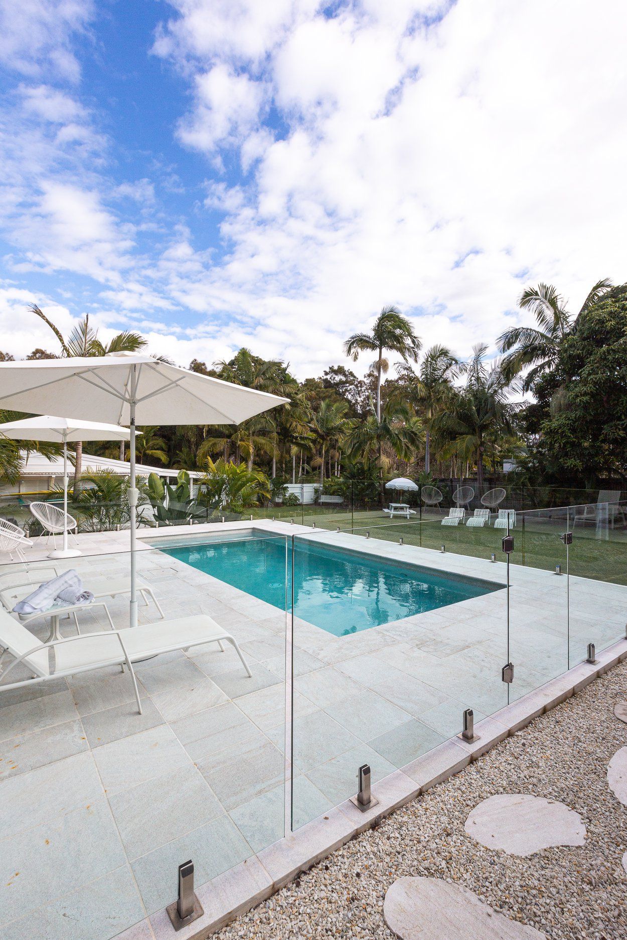 A Large Swimming pool with Umbrellas and chairs Around it — Profile Pools & Landscaping In Byron Bay, NSW