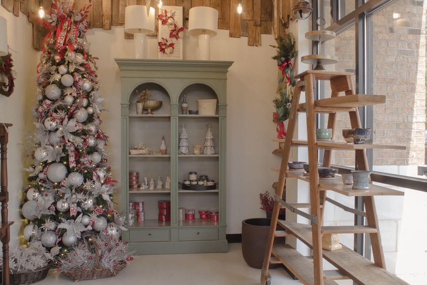 Festive room with a decorated Christmas tree, display cabinet, and wooden ladder by a window