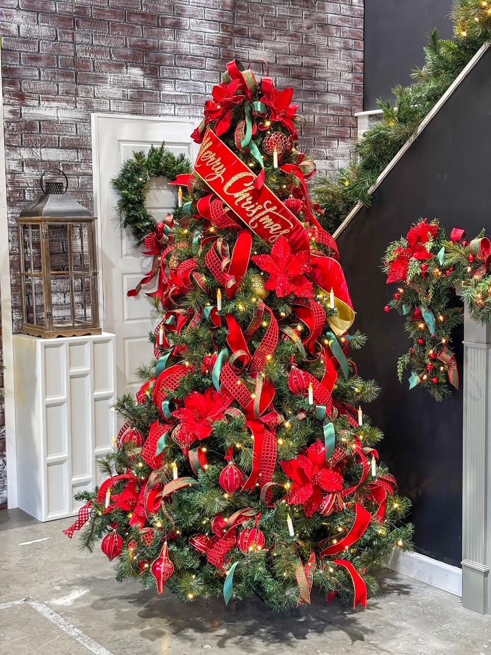 Decorated Christmas tree with red ribbons and ornaments in a festive indoor display area