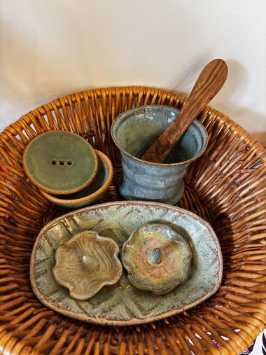 Wicker basket with handmade ceramic dishes and bowls in muted green and brown tones