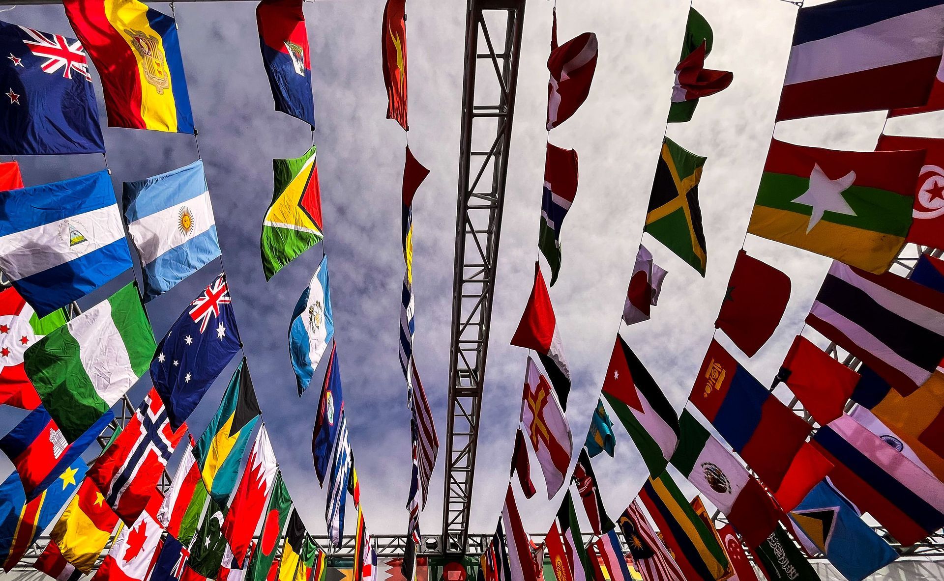 Rows of colorful international flags fluttering overhead against a bright sky