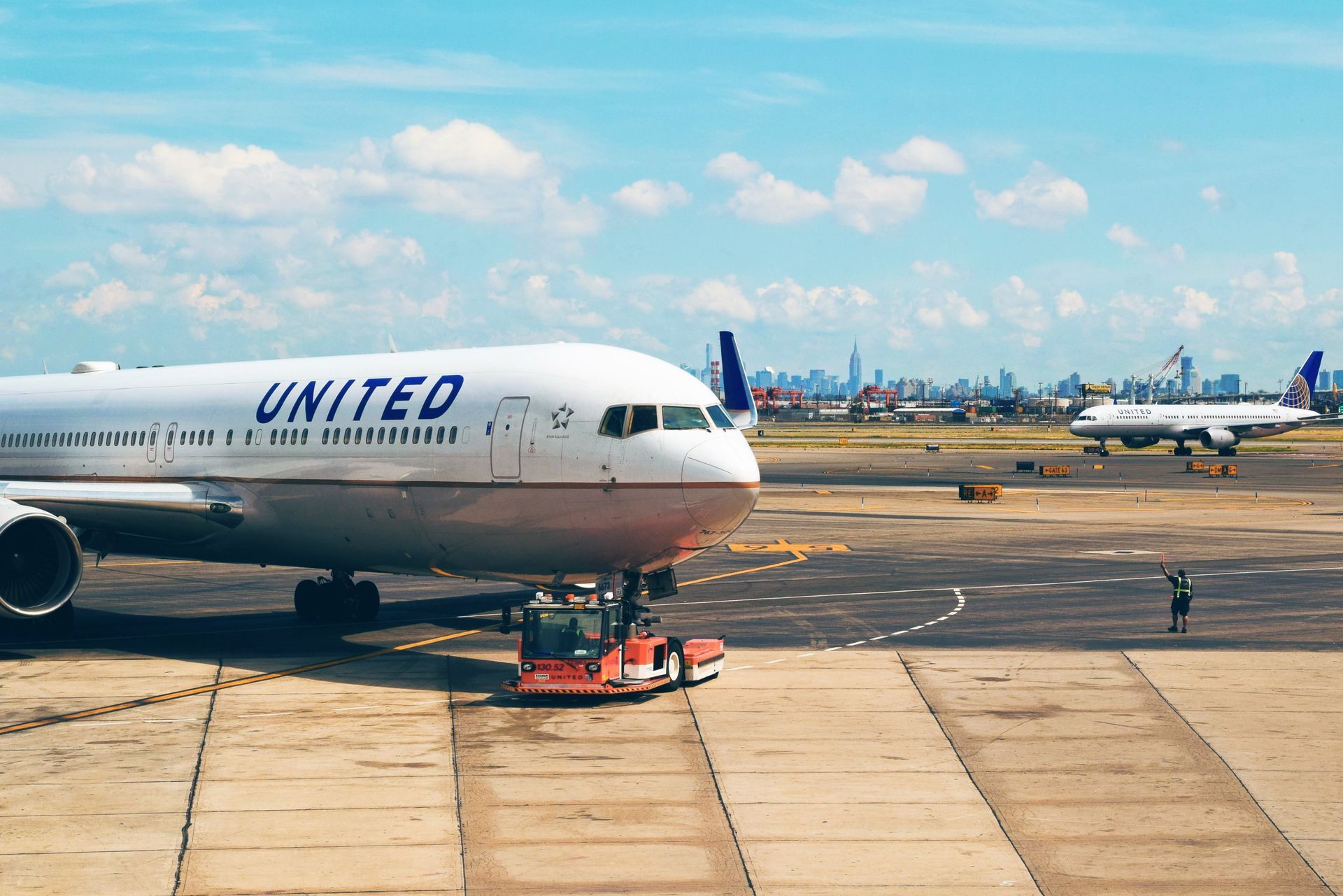 United Airlines jet at airport gate with skyline in the distance