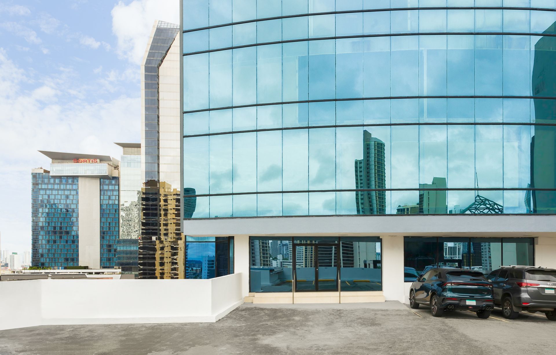 Un edificio con muchas ventanas y coches aparcados delante.