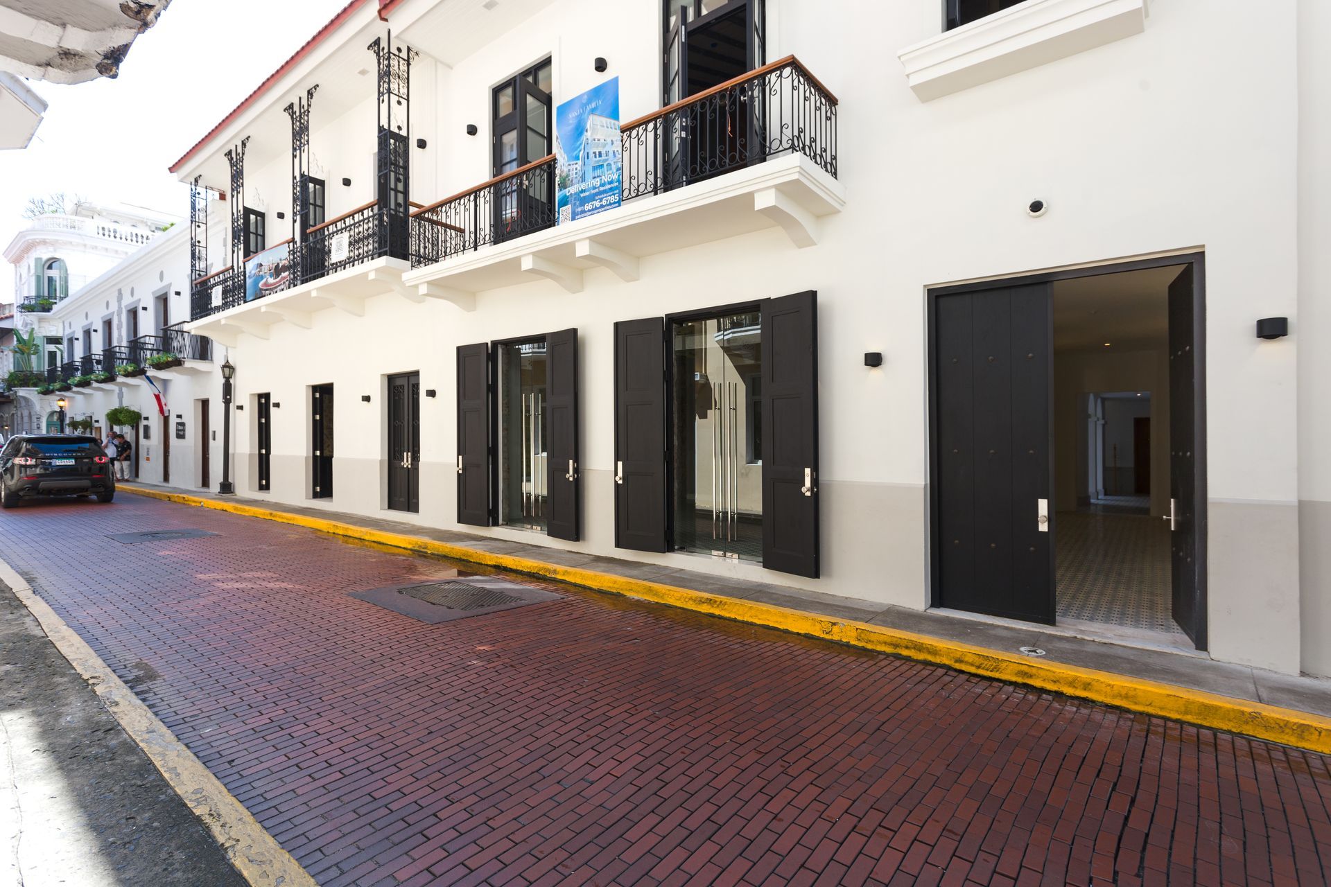 Un coche está aparcado delante de un edificio blanco en una calle adoquinada.