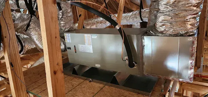 Insulated HVAC ductwork installed between exposed attic rafters and wooden framing