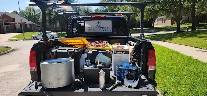 Pickup truck bed loaded with cleaning supplies and equipment in a suburban driveway