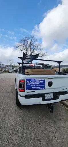 White pickup truck with a ladder rack and blue sign parked on a cracked lot under a cloudy sky