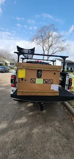 Cardboard box and equipment strapped to the back of a pickup truck on a residential street
