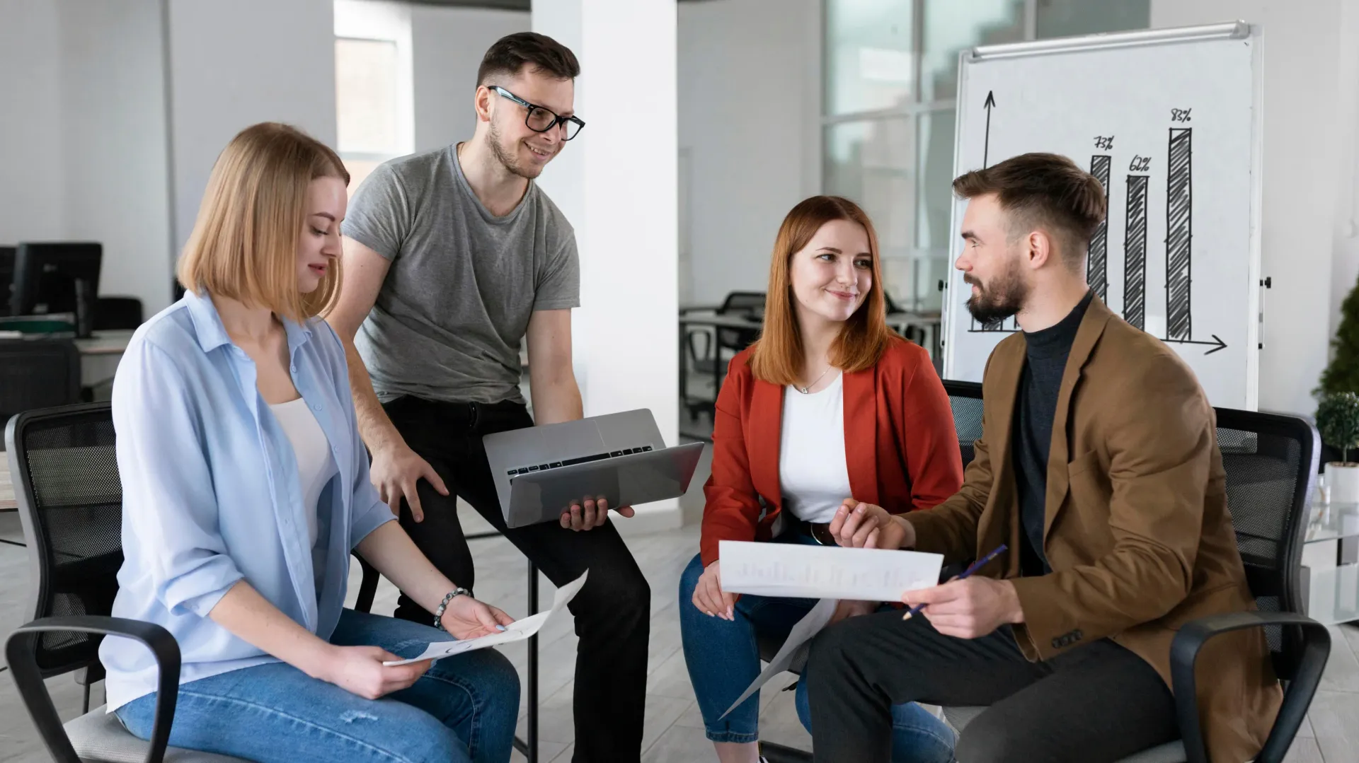 A group of people are sitting in a circle in an office having a meeting.
