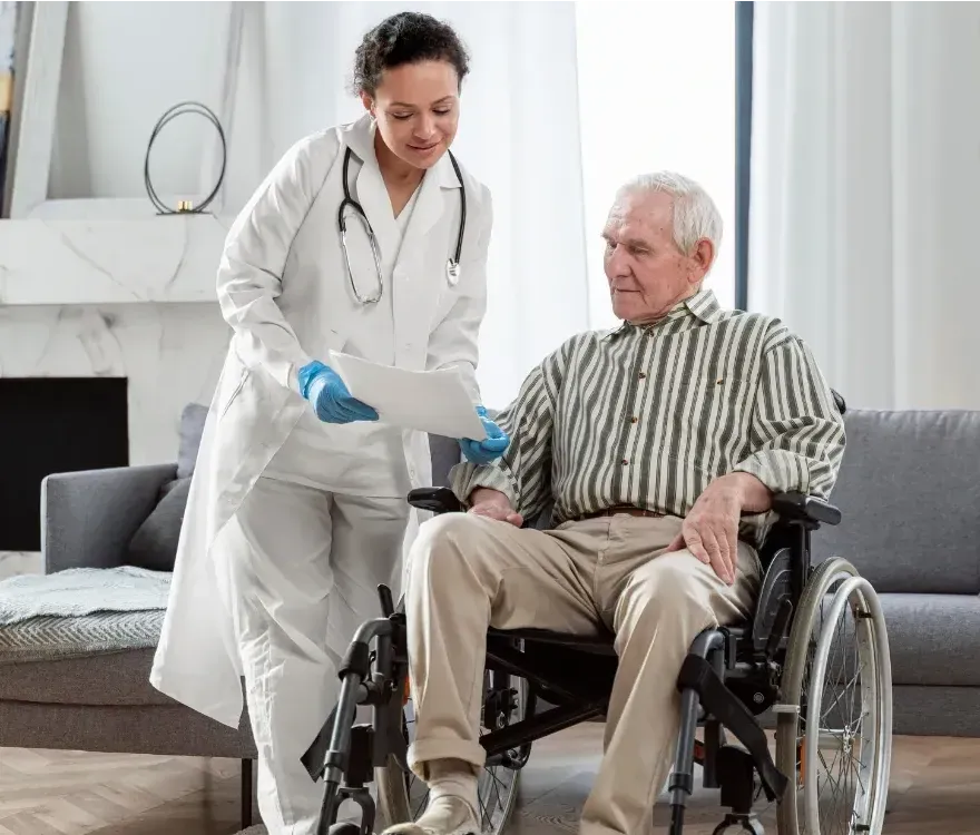 A doctor is talking to an elderly man in a wheelchair.
