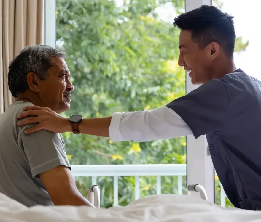 A nurse is talking to an elderly man in a hospital bed.