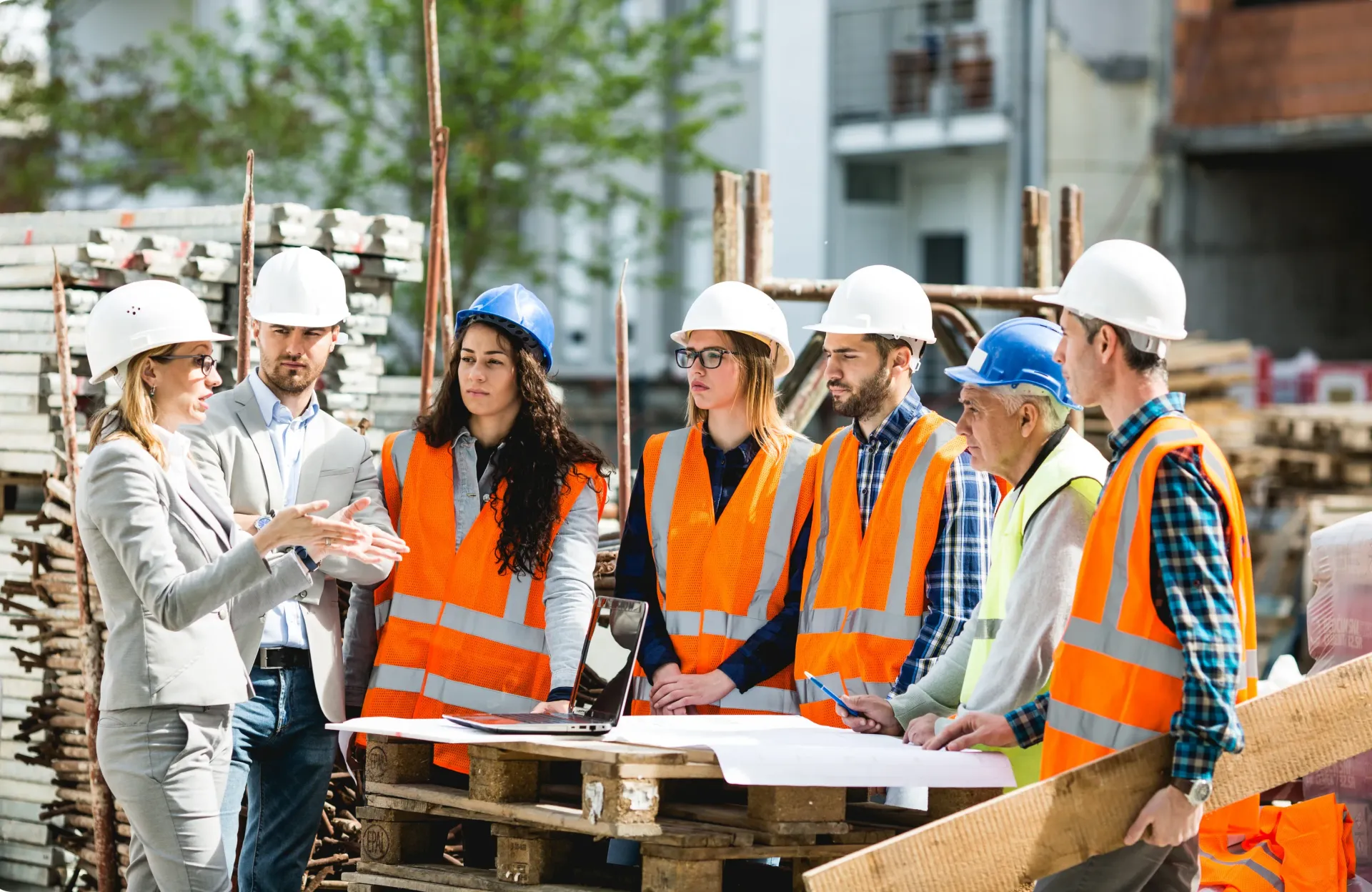 A group of construction workers are standing around a woman on a construction site.