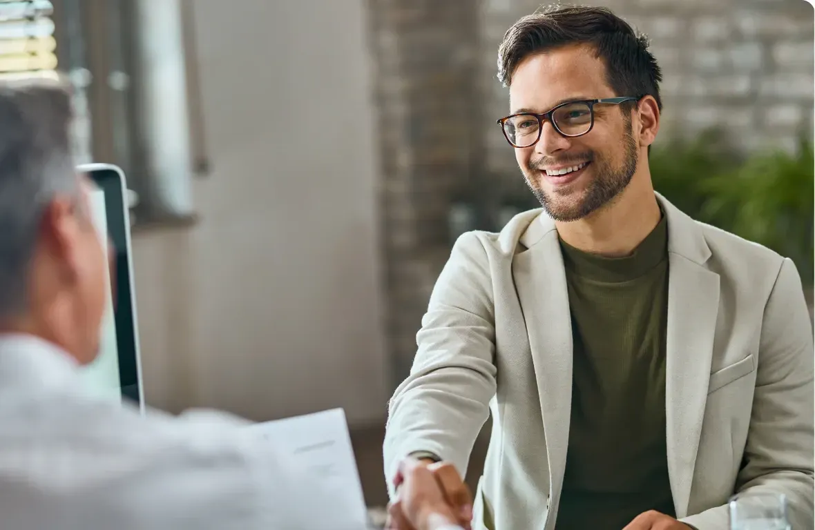 A man is shaking hands with another man during a job interview.