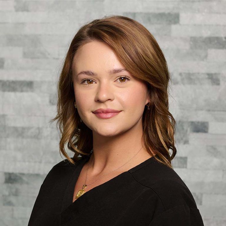 Portrait of a smiling woman in a black top against a gray textured background