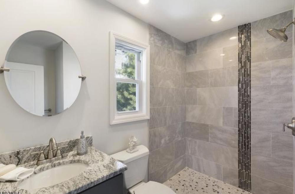 Elegant bathroom remodel with tiled walk-in shower and granite countertop by DMF Construction in Scotch Plains, NJ