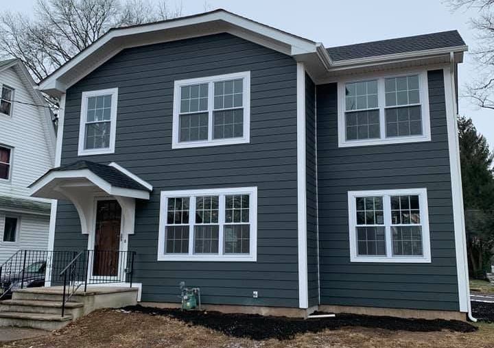 Backyard view of home with new blue siding installation and patio area, completed by DMF Construction in Scotch Plains, NJ.