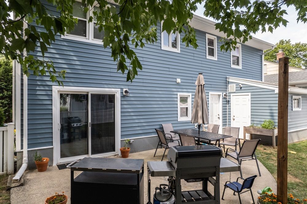 Backyard view of home with new blue siding installation and patio area, completed by DMF Construction in Scotch Plains, NJ.
