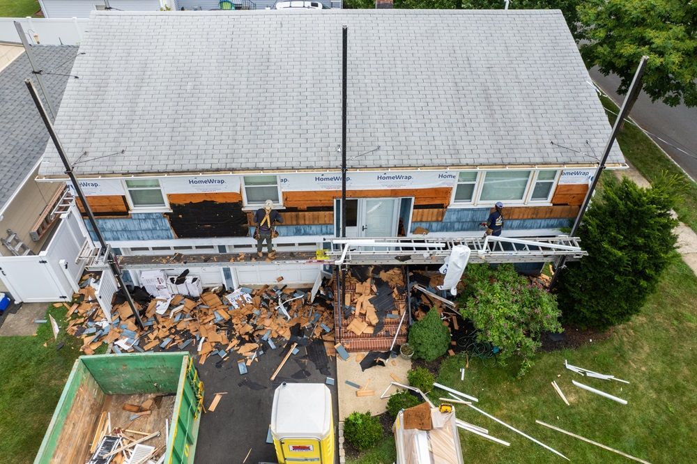Home exterior under renovation with old siding removed and workers preparing for new installation by DMF Construction.