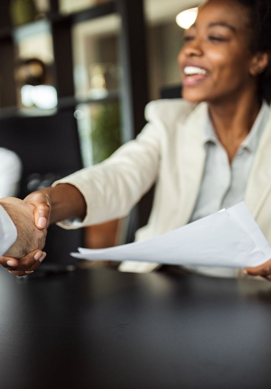 A woman is smiling while shaking hands with a man