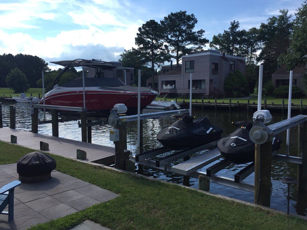 A boat is sitting on a lift next to a jet ski