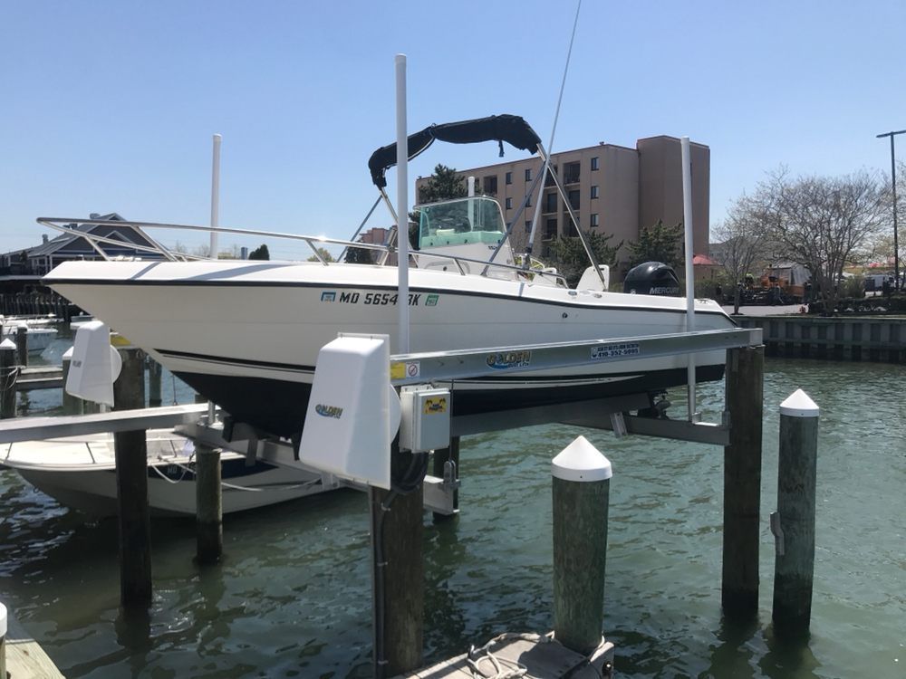 A boat is sitting on a lift in the water.