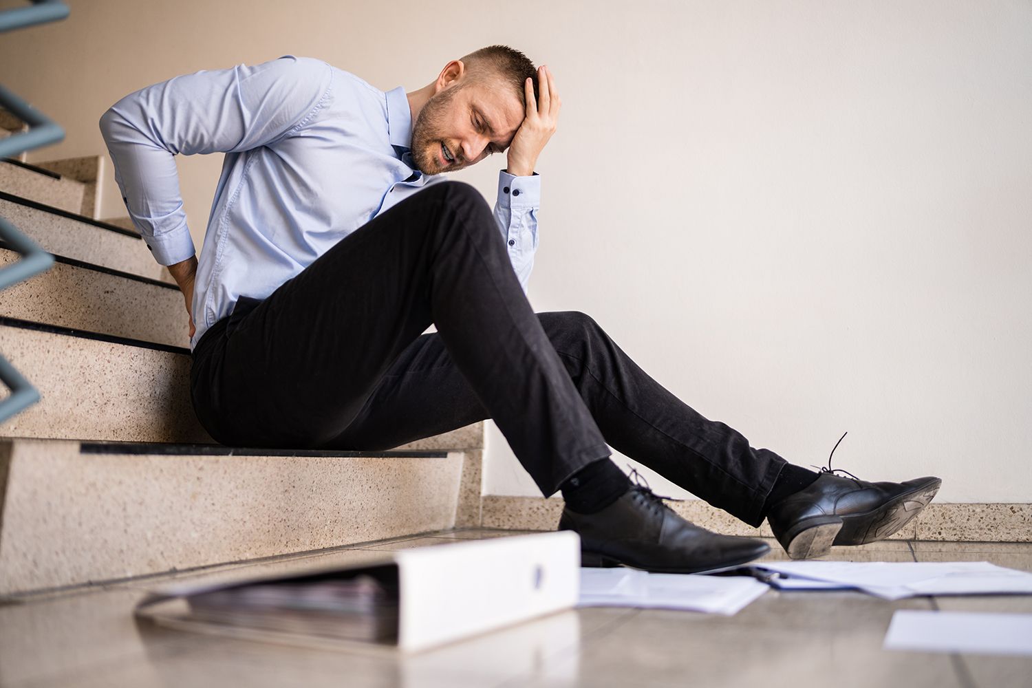 Man holding his back after falling on stairs, needing a slip and fall lawyer.
