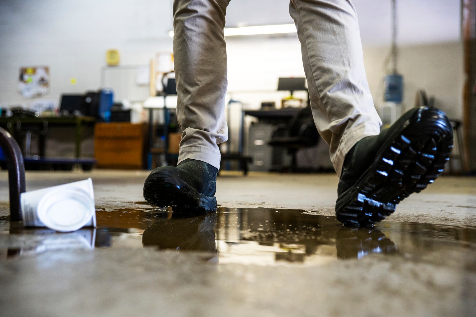 A worker in a warehouse slipping on spilled liquid, representing the need for a slip and fall lawyer.