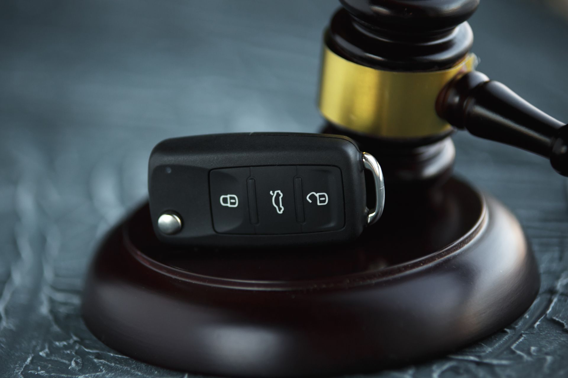 Car key on judge gavel symbolizing auto law, vehicle ownership rulings and car auction cases.