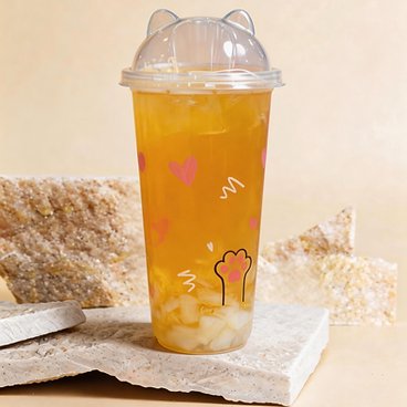 Clear cup of orange iced drink with domed lid, heart doodles, and lemon slices on stone blocks